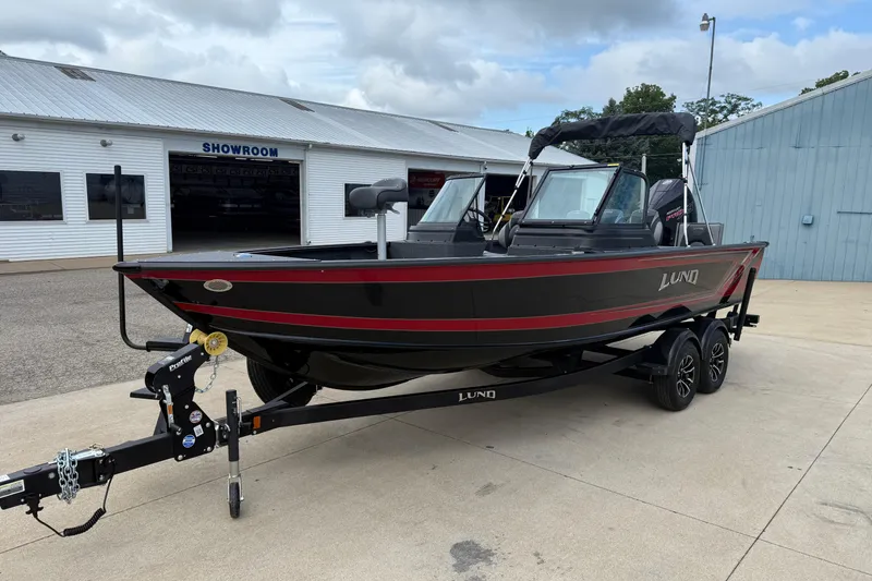 Slide: The Image of 2026 Lund 2075 Impact XS boat on trailer outside a showroom, black with red accents. - 3
