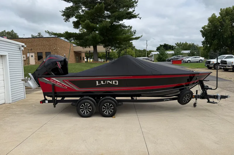 Slide: The Image of 2026 Lund 2075 Impact XS boat with cover on trailer, parked outdoors. - 30