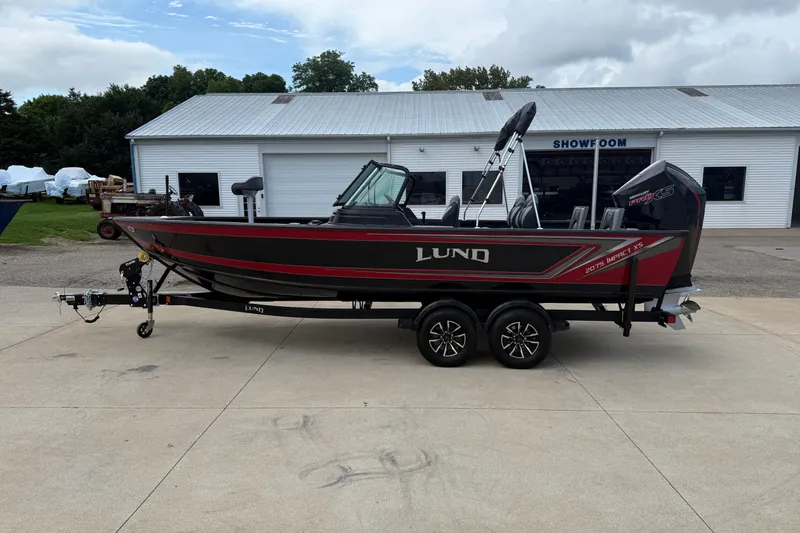 Slide: The Image of 2026 Lund 2075 Impact XS boat on trailer outside showroom, side view. - 4