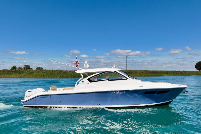 The Image of 2020 Pursuit DC 365 Dual Console boat cruising on clear blue water under a sunny sky. - 0