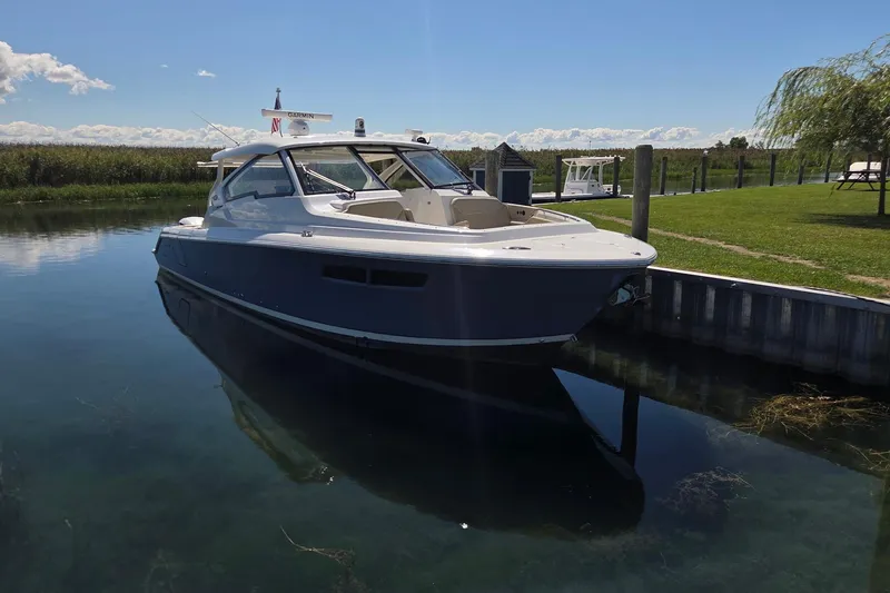 Slide: The Image of 2020 Pursuit DC 365 Dual Console boat docked in calm waters on a sunny day. - 10