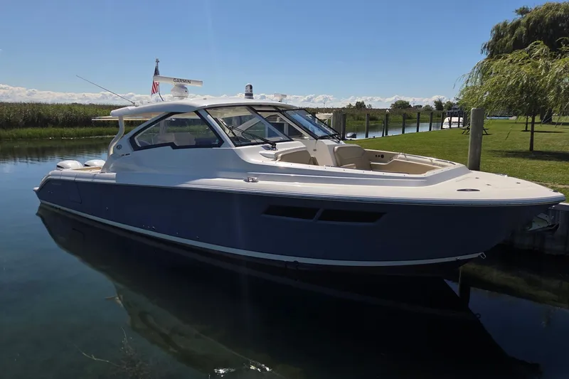 Slide: The Image of 2020 Pursuit DC 365 Dual Console boat docked on a sunny day. - 2