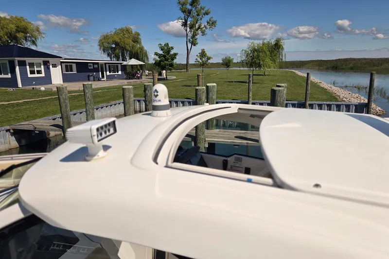 Slide: The Image of 2020 Pursuit DC 365 Dual Console boat docked near a lakeside house. - 21