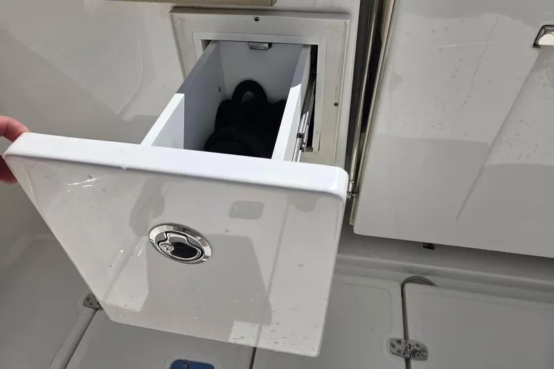 Slide: The Image of 2020 Pursuit DC 365 Dual Console boat storage drawer open, showcasing interior space. - 26