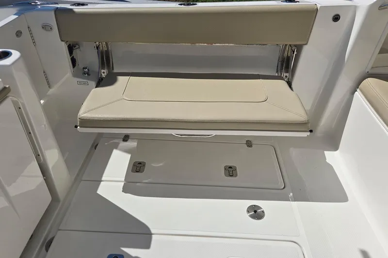 Slide: The Image of 2020 Pursuit DC 365 Dual Console boat interior with foldable beige seat and storage compartments. - 29