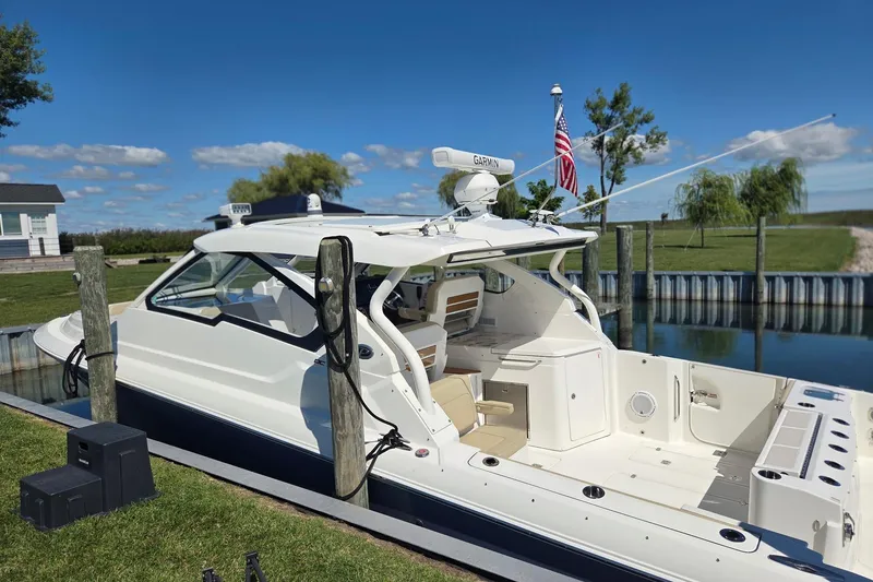 Slide: The Image of 2020 Pursuit DC 365 Dual Console boat docked by a serene lakeside. - 3