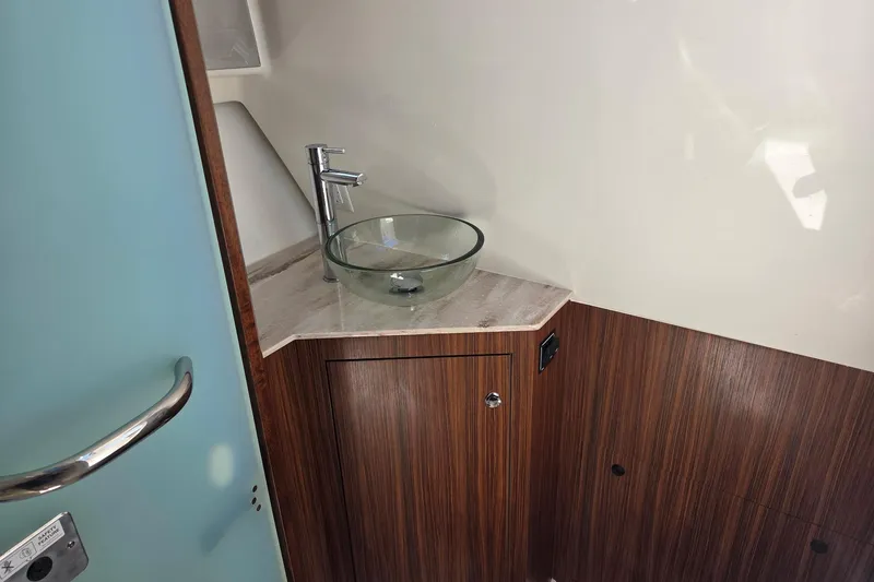 Slide: The Image of 2020 Pursuit DC 365 Dual Console boat interior with modern glass sink and wood cabinetry. - 49