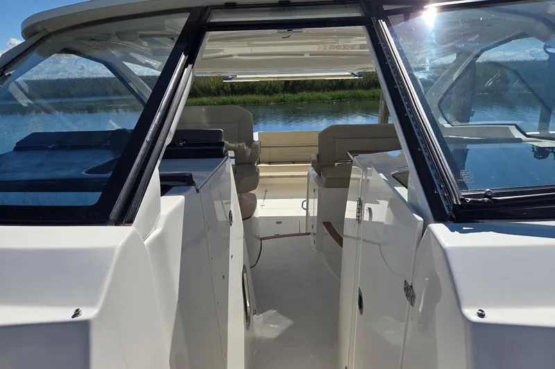 Slide: The Image of 2020 Pursuit DC 365 Dual Console boat interior with seating, on a calm water backdrop. - 57