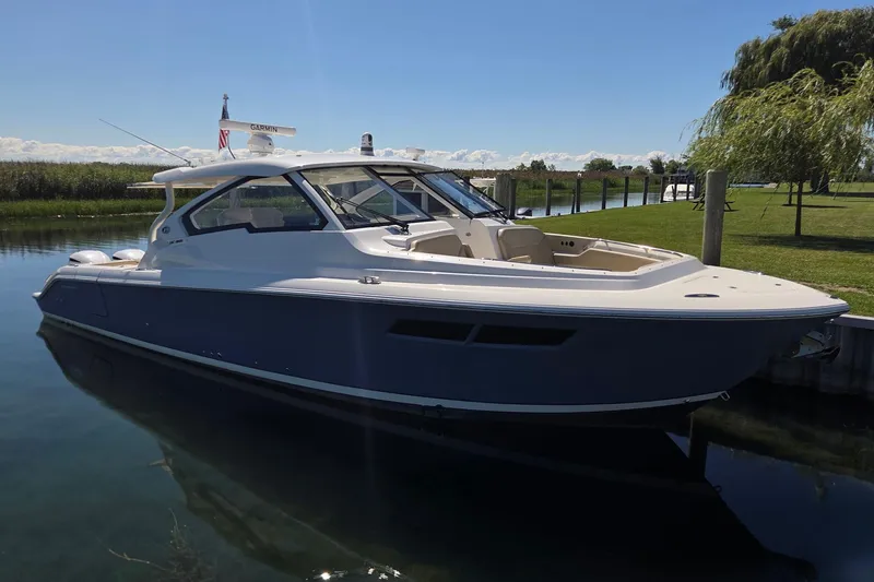 Slide: The Image of 2020 Pursuit DC 365 Dual Console boat docked on a sunny day. - 6