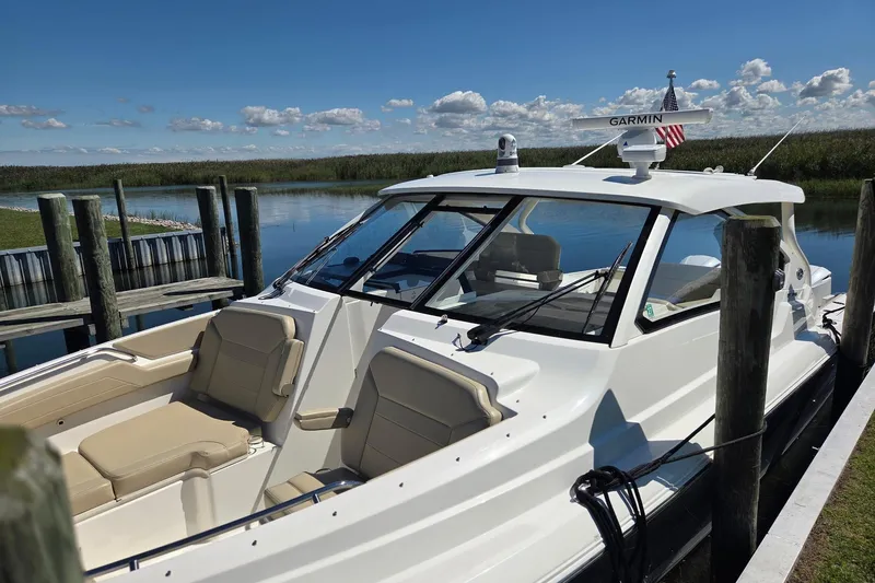 Slide: The Image of 2020 Pursuit DC 365 Dual Console boat docked by a serene lake. - 60