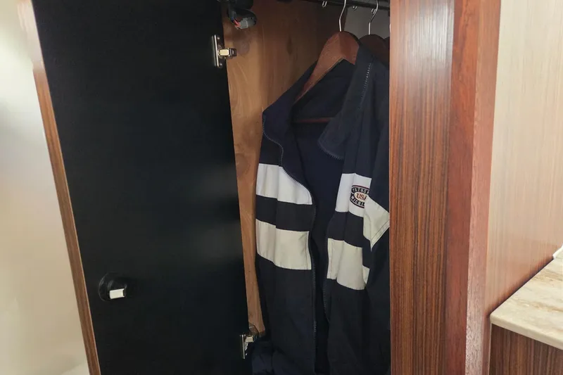 Slide: The Image of Wooden closet on 2020 Pursuit DC 365 Dual Console boat with hanging jacket. - 63