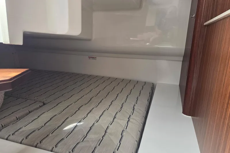 Slide: The Image of 2020 Pursuit DC 365 Dual Console cabin interior with cushioned seating and wooden accents. - 65