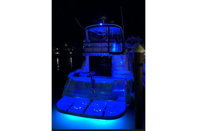 Slide: The Image of 2002 Sea Ray 550 Sedan Bridge yacht illuminated with blue lights at night. - 2