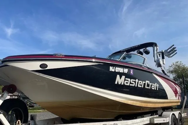Slide: The Image of 2013 MasterCraft X-25 boat with red and white design, parked outdoors. - 14