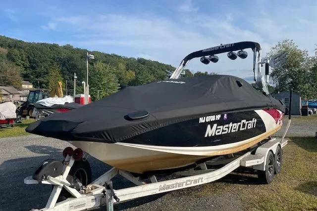 Slide: The Image of 2013 MasterCraft X-25 boat on trailer with cover, parked outdoors. - 19