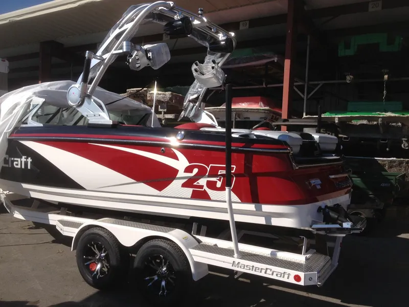 Slide: The Image of 2013 MasterCraft X-25 boat on trailer, red and white design, parked outdoors. - 22