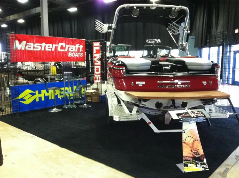 Slide: The Image of 2013 MasterCraft X-25 boat displayed indoors with promotional banners and accessories. - 25