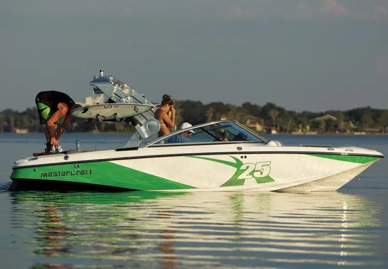 Slide: The Image of 2013 MasterCraft X-25 boat on calm water with people onboard, featuring green and white design. - 31