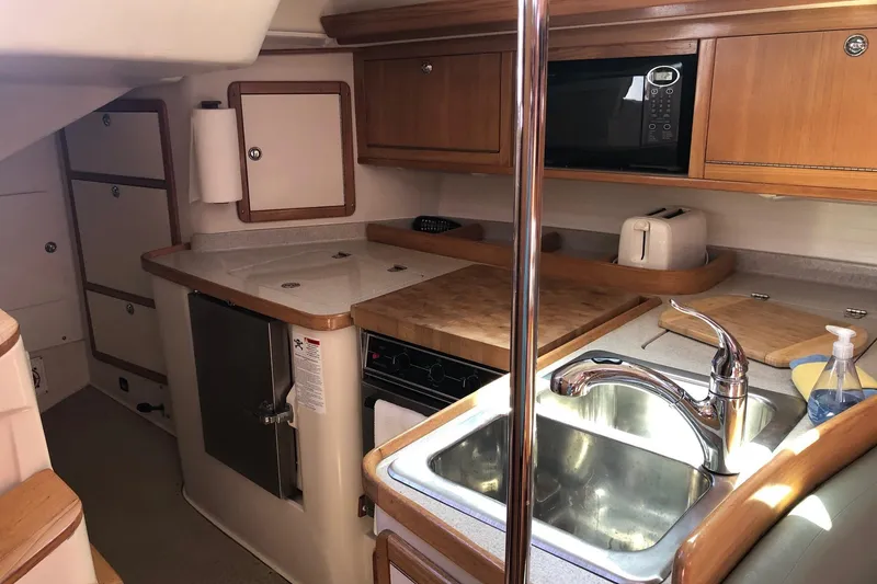 Slide: The Image of 2008 Catalina 42 MkII yacht kitchen with sink, stove, and wooden cabinetry. - 10