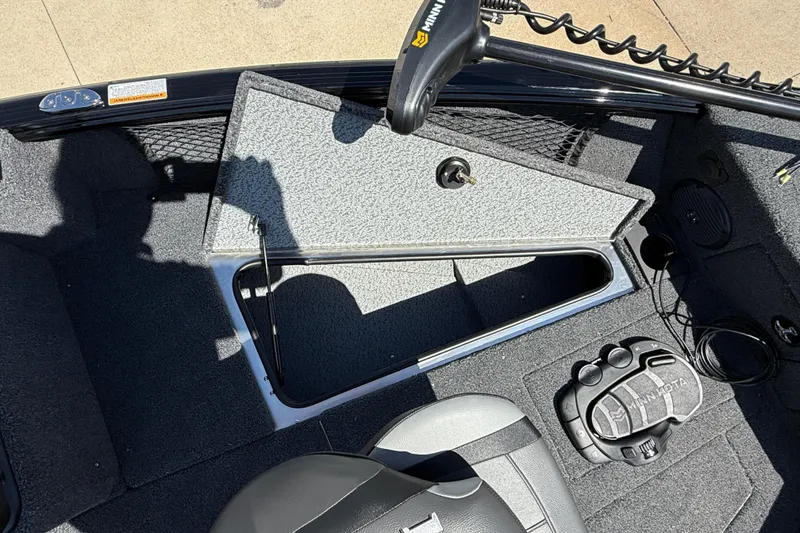 Slide: The Image of 2026 Lund 1875 Impact XS Sport boat interior with storage compartment and Minn Kota foot pedal. - 12