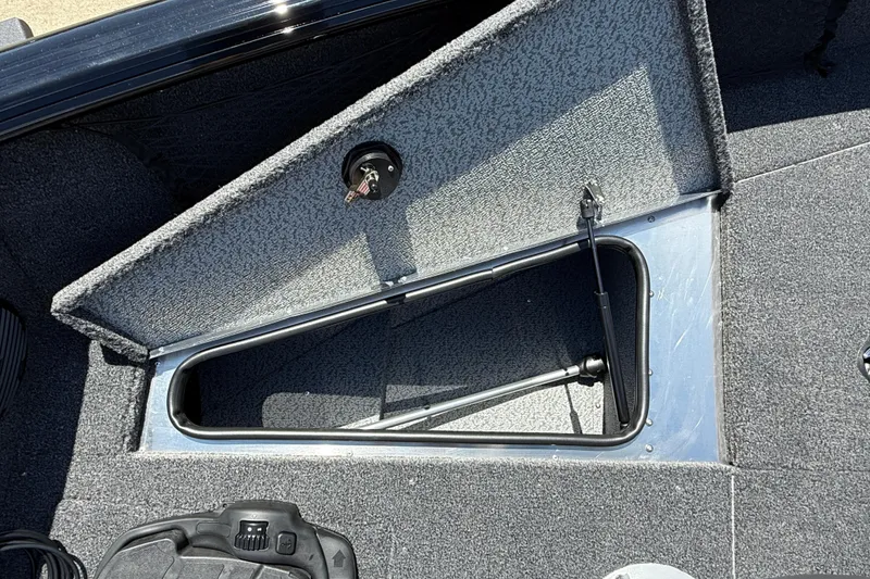 Slide: The Image of Open storage compartment in 2026 Lund 1875 Impact XS Sport boat, featuring carpeted interior. - 13