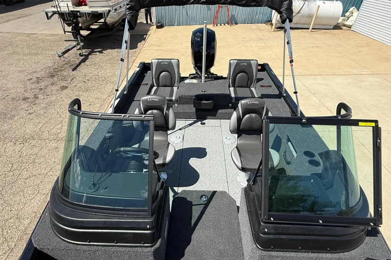 Slide: The Image of 2026 Lund 1875 Impact XS Sport boat with seating and windshield, parked outdoors. - 15