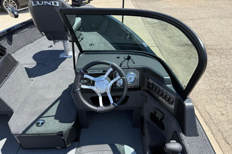 Slide: The Image of 2026 Lund 1875 Impact XS Sport boat interior with steering wheel and dashboard controls. - 19