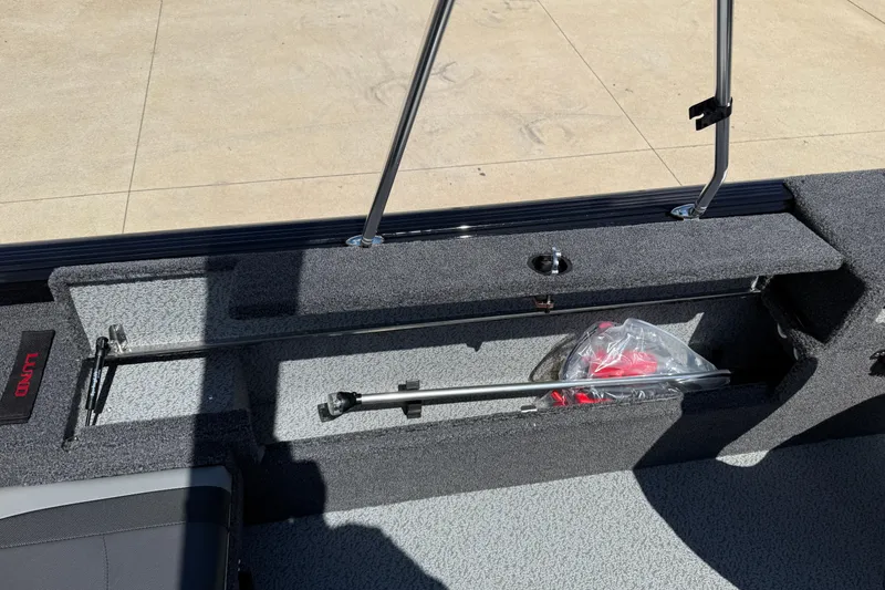 Slide: The Image of 2026 Lund 1875 Impact XS Sport boat interior storage compartment with fishing rod holder. - 26