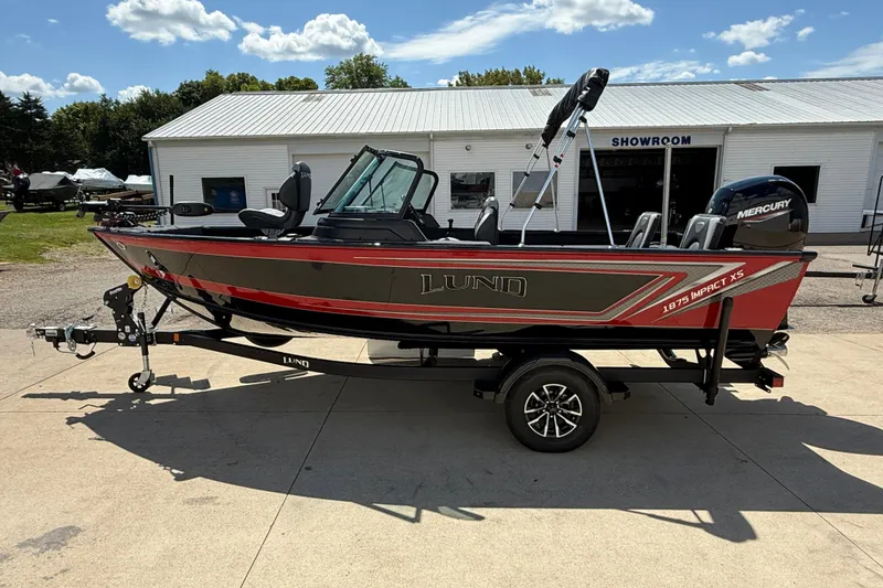 Slide: The Image of 2026 Lund 1875 Impact XS Sport boat on trailer outside showroom. - 5