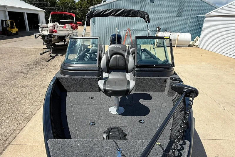 Slide: The Image of 2026 Lund 1875 Impact XS Sport boat with seating and windshield, parked outdoors. - 9