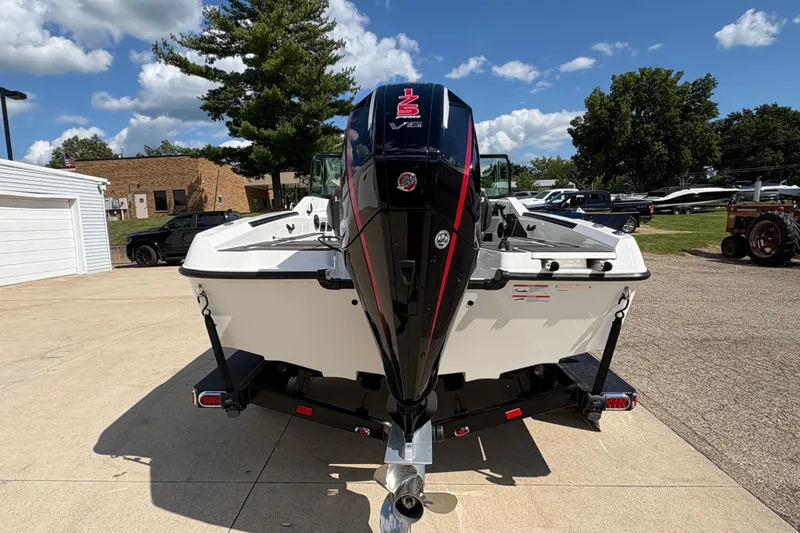 Slide: The Image of 2026 Lund 185 Impact GL boat with powerful V6 engine, parked outdoors on a sunny day. - 2
