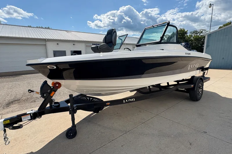 Slide: The Image of 2026 Lund 185 Impact GL boat on trailer, parked outdoors under a cloudy sky. - 5