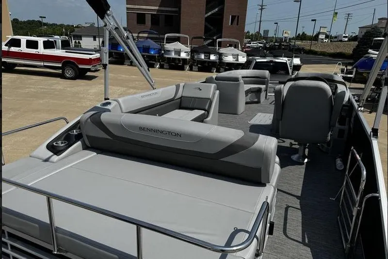 Slide: The Image of 2025 Bennington 25 SXSB pontoon boat with spacious seating, parked outdoors. - 18