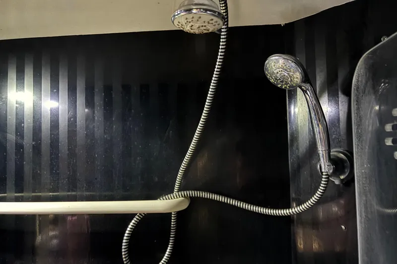 Slide: The Image of Shower area in 1986 Maiora Phantom yacht with dual showerheads and sleek black paneling. - 30