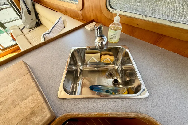 Slide: The Image of Compact kitchen sink area on 2001 Sabre Sabreline 34 boat with soap and sponges. - 32