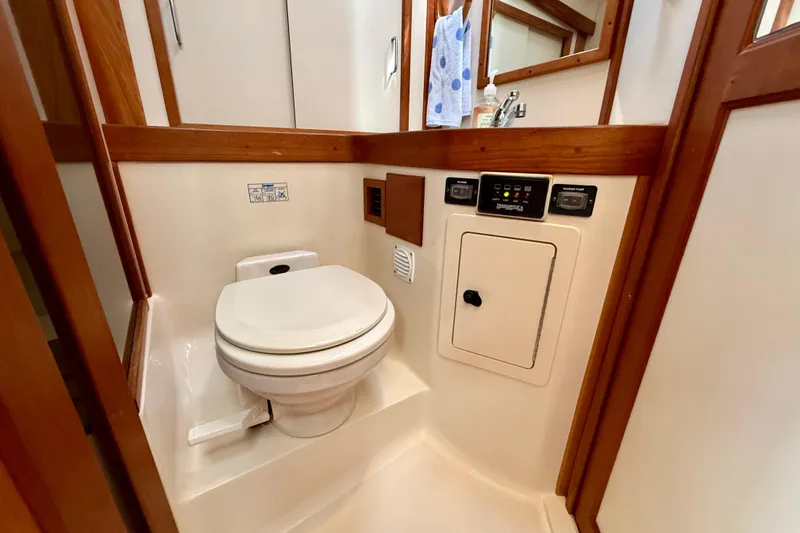 Slide: The Image of 2001 Sabreline 34 yacht bathroom with toilet, wooden accents, and control panels. - 39