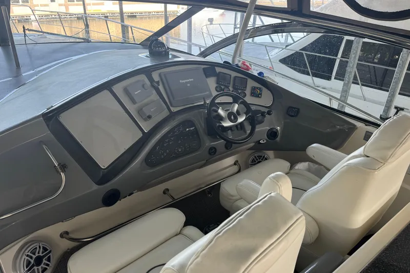 Slide: The Image of 2006 Cruisers Yachts 560 Express helm with modern controls and white seating. - 14