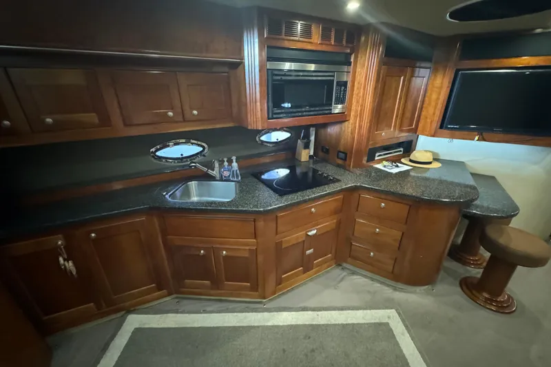 Slide: The Image of Luxurious 2006 Cruisers Yachts 560 Express interior kitchen with wood cabinetry and modern appliances. - 15
