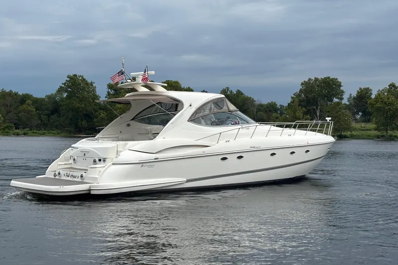 Slide: The Image of 2006 Cruisers Yachts 560 Express on a serene lake with lush green trees. - 4