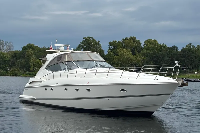 The Image of 2006 Cruisers Yachts 560 Express on calm water with lush green background. - 0