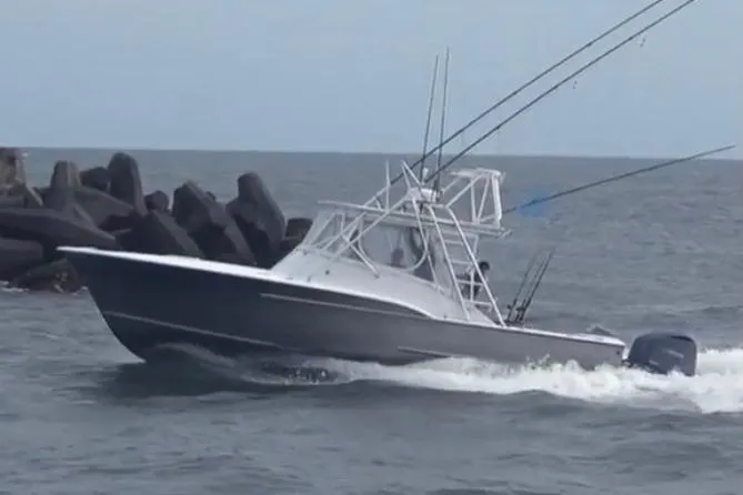 Slide: The Image of 2003 Shearline 30 Express boat navigating through ocean waves near rocky breakwater. - 2