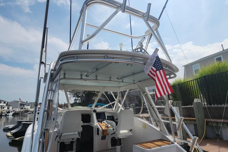 Slide: The Image of 2003 Shearline 30 Express boat docked, featuring a sleek design and American flag. - 33