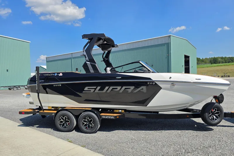 Slide: The Image of 2026 Supra SA boat on trailer, parked outdoors under blue sky. - 5
