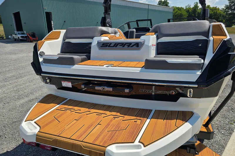 Slide: The Image of 2026 Supra SA boat with sleek design and wooden deck, parked outdoors. - 7