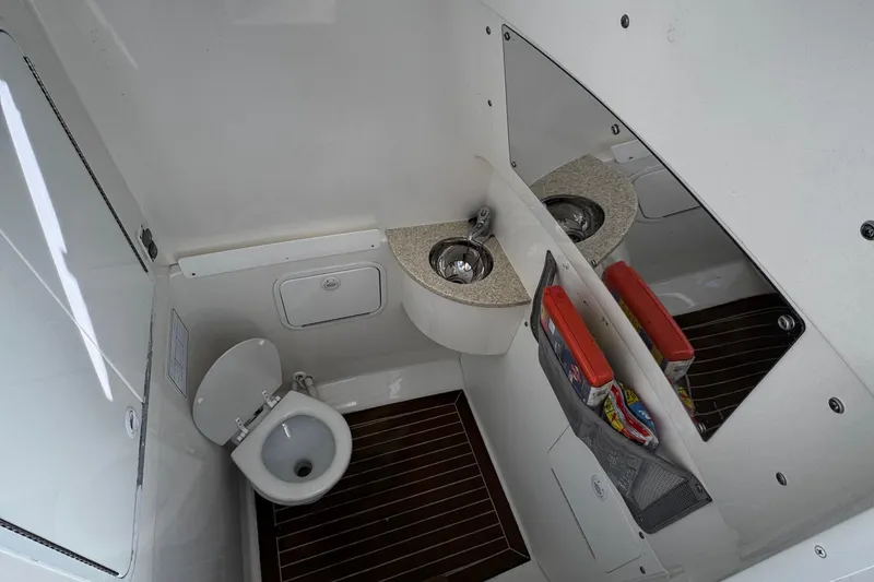 Slide: The Image of 2015 Regulator 28 Forward Seating boat bathroom with sink, toilet, and storage. - 28