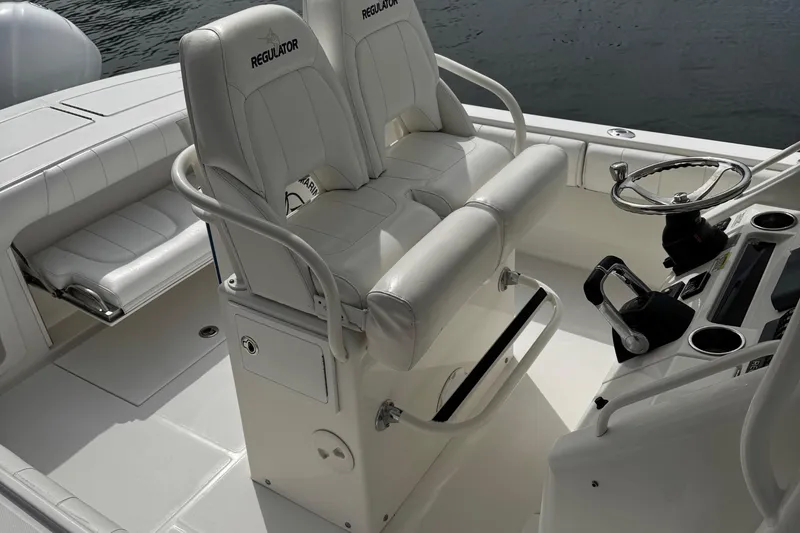 Slide: The Image of 2015 Regulator 28 Forward Seating boat interior with helm, steering wheel, and cushioned seats. - 6