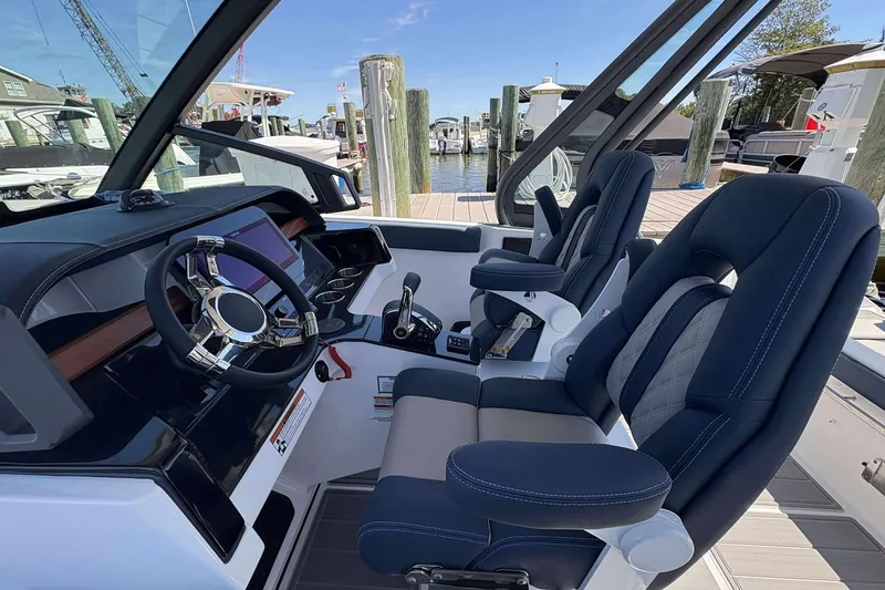 Slide: The Image of 2026 Monterey 25 Elite boat cockpit with modern steering and dual seats at marina. - 12