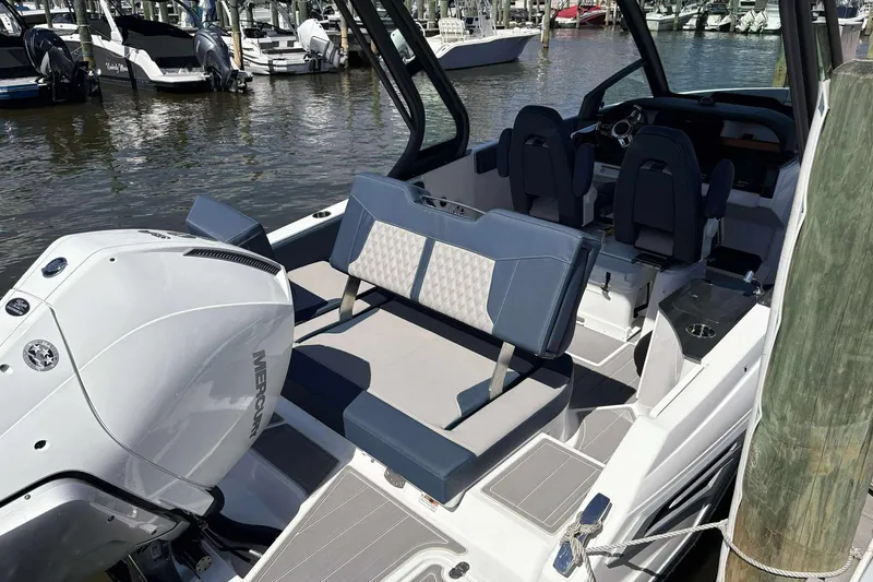 Slide: The Image of 2026 Monterey 25 Elite boat with modern seating and powerful Mercury engine at a marina. - 13