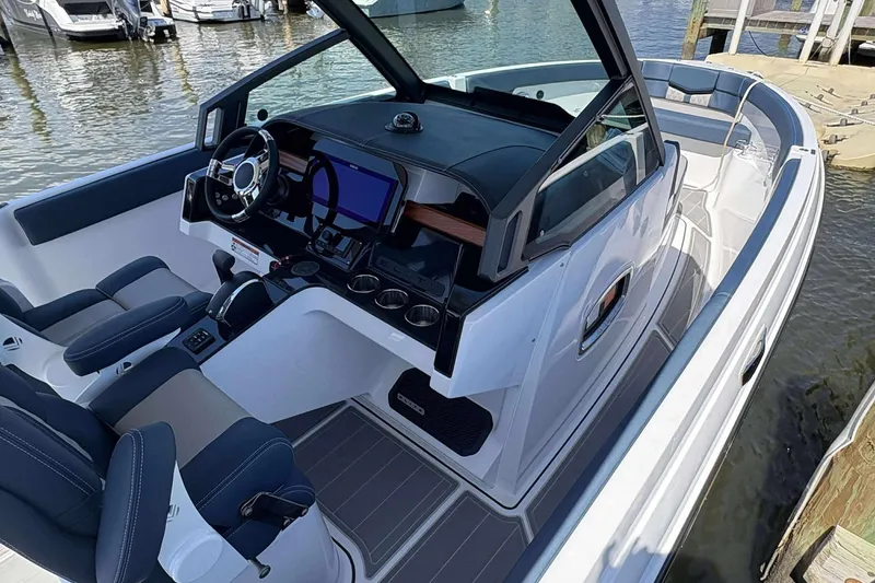 Slide: The Image of 2026 Monterey 25 Elite boat interior with modern dashboard and seating at a marina. - 4