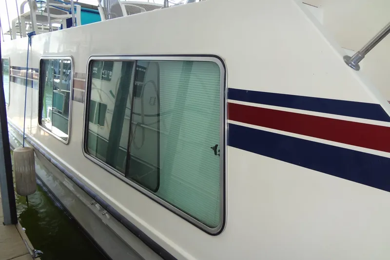 Slide: The Image of 1995 Harbor Master 52 boat with red and blue stripes, docked in water. - 11